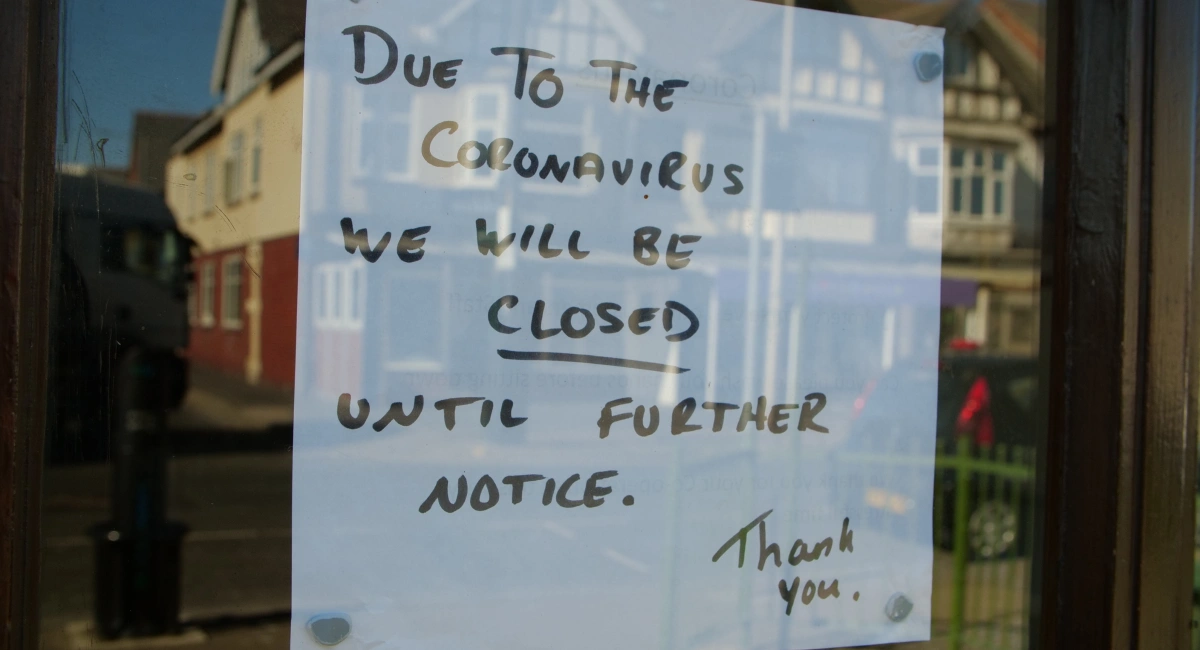 Closed Sign on Store Window due to covid - sign reads "Due to the coronavirus we will be closed until further notice"